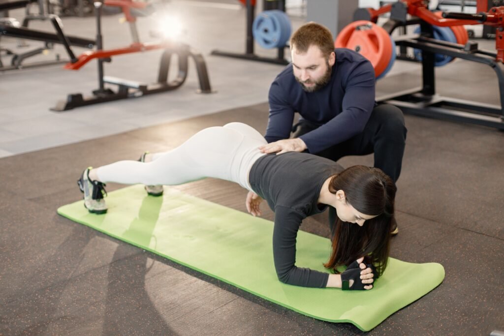 caucasian woman doing excercisses at gym with personal male trai